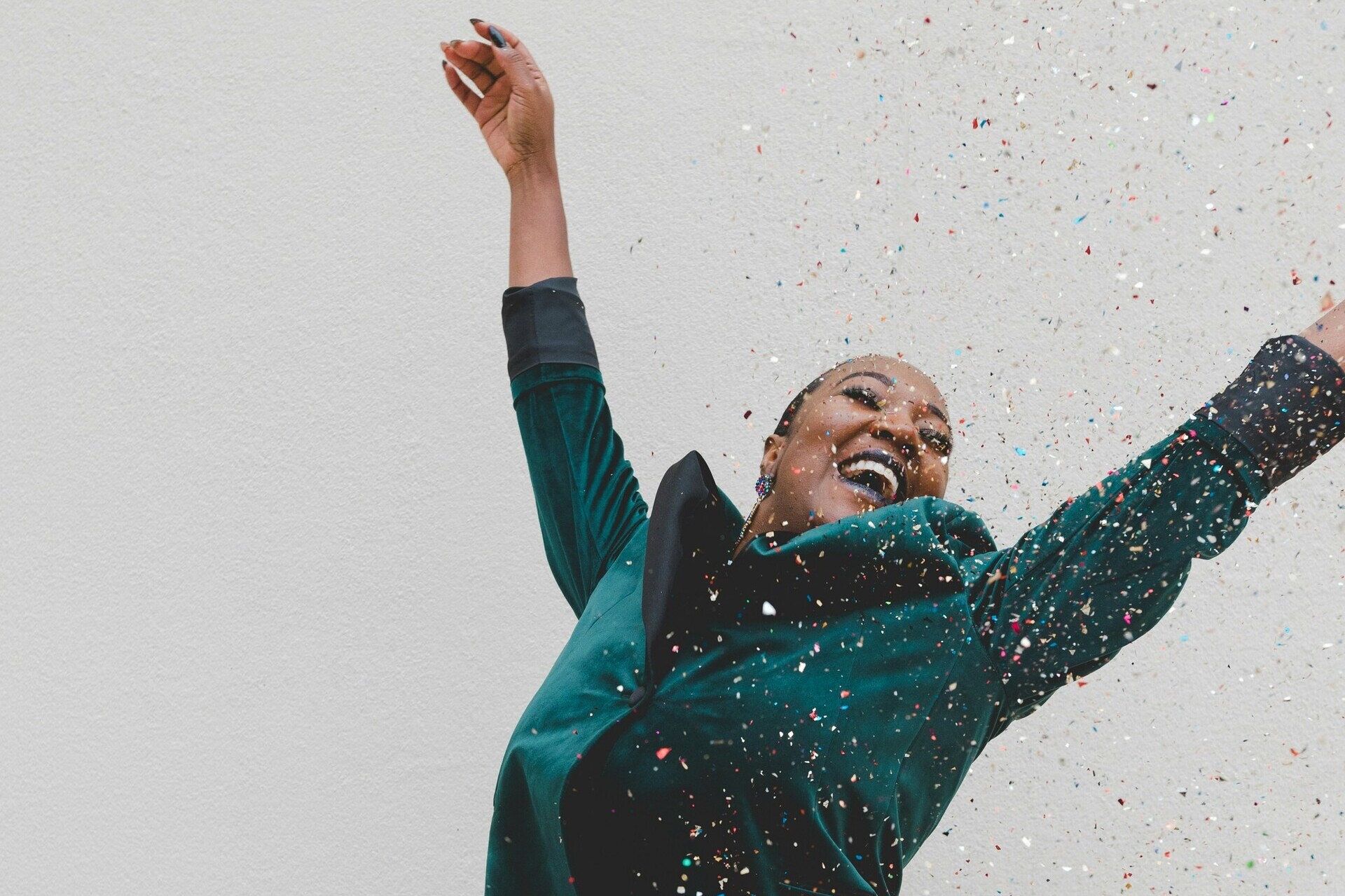 Frau steht mit erhobenen Armen, lacht, Blick nach oben gerichtet